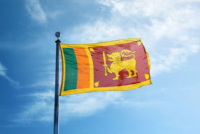 Low angle view of yellow flag against blue sky