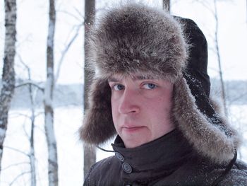 Portrait of young man wearing hunter cap standing on snowy field