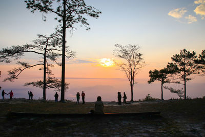 Silhouette people on land against sky during sunset