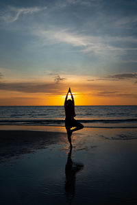 Silhouette of woman meditate on beach at sunset