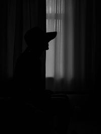 Silhouette of woman sitting in front of window