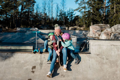 Mom and her kids laughing having fun and playing at skatepark