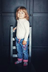 Portrait of cute girl standing against wall
