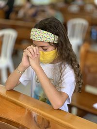 Cute girl wearing mask praying at church
