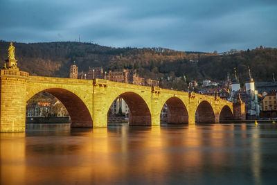 Arch bridge over river against sky