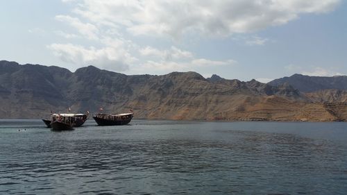 Boats in river with mountain range in background