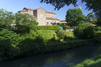 River amidst trees and buildings against sky