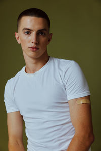 Portrait of young man standing against wall