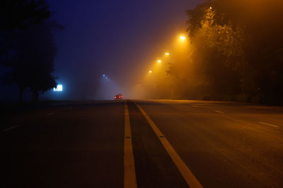 Road amidst trees against sky at night