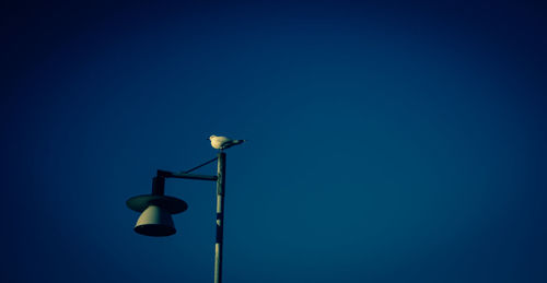 Low angle view of illuminated street light against clear blue sky