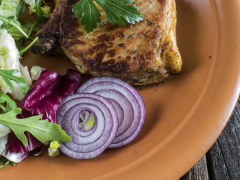 Close-up of roasted pork chop with salad in plate on table