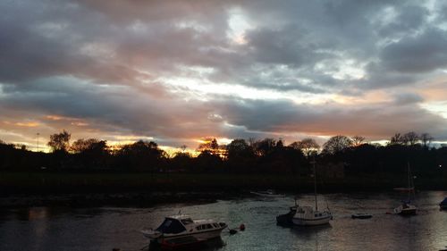 Boats moored in lake against sky during sunset