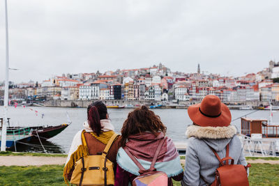 Rear view of women sitting by cityscape against sky