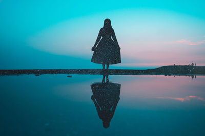 Silhouette woman at beach against sky at night