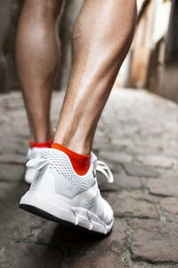 Close-up of legs walking on cobblestone