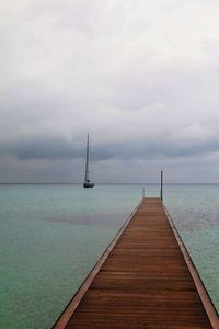 Sailboat on pier over sea against sky