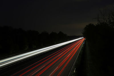 Light trails on road against sky at night