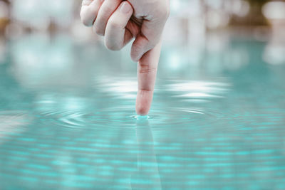 Cropped finger dipping in swimming pool