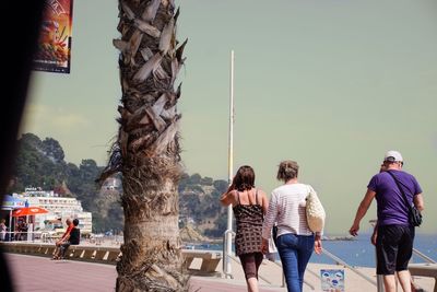 Rear view of people walking on shore against sky