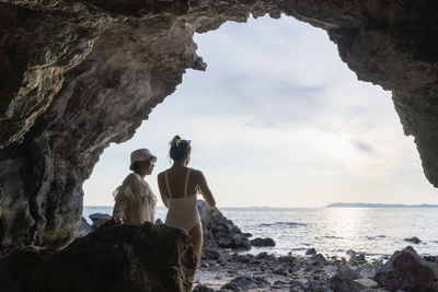 Rear view of woman sitting on rock at beach