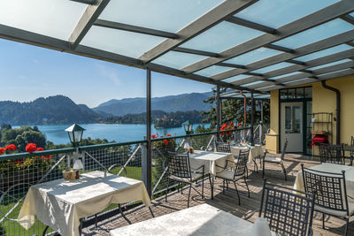 Chairs and tables in restaurant by sea against sky