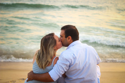 Rear view of couple kissing at beach