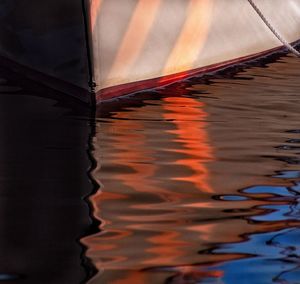 Reflection of boat moored on lake during sunset