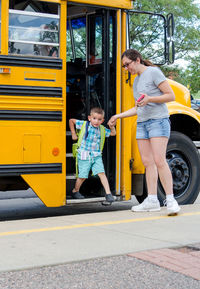 Mom helping small son off a school bus
