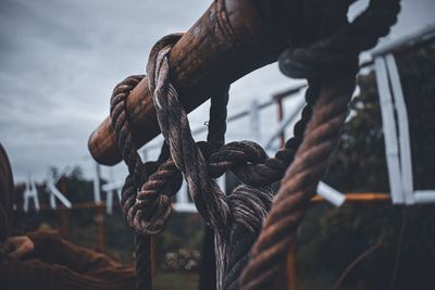 Close-up of rope tied to rusty metal chain against sky