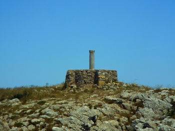 Low angle view of built structure on mountain against clear blue sky