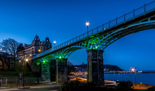 Illuminated bridge over river against sky at night