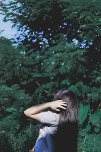 Rear view of young woman standing against trees