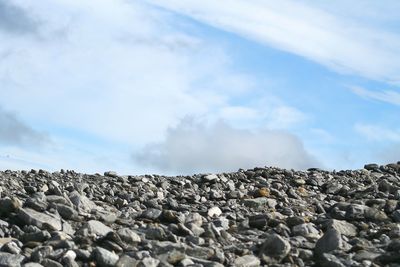 Rocks on landscape against cloudy sky