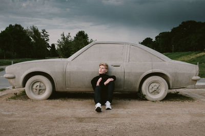 Portrait of teenage girl standing by car