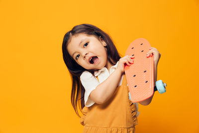 Portrait of cute girl standing against yellow background