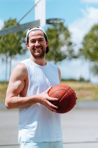 Man holding ball while standing against basketball