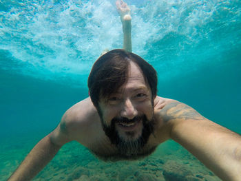 Portrait of shirtless man swimming in pool