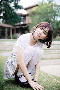 Portrait of young woman crouching at public park