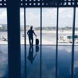 Rear view of silhouette person standing with luggage