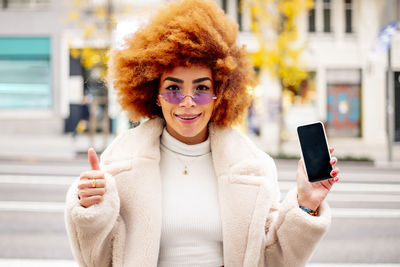 Portrait of smiling young woman using mobile phone in city