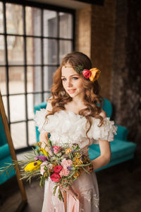 Portrait of beautiful woman standing by potted plant