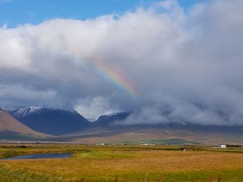 Scenic view of rainbow over field against sky