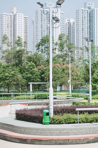 Street light by trees in park against buildings in city