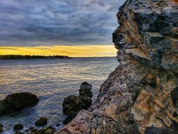 Rock formation on beach against sky during sunset