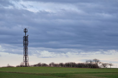 Communications tower on field against sky