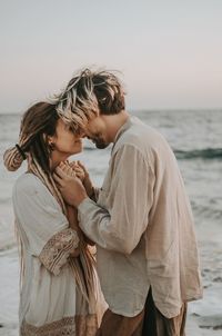 Rear view of couple standing at sea against sky