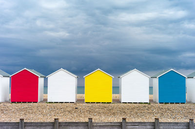 Colorful beach huts against cloudy sky