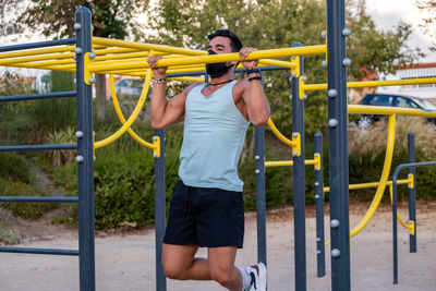 Young man wearing mask exercising at playground