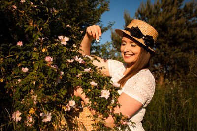 Portrait of smiling young woman wearing hat against plants