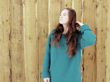 Woman with long hair standing against wooden fence